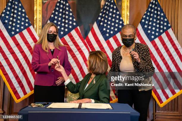 Speaker of the House Nancy Pelosi hands a pen used to sign H.R. 3325 to Rep. Jennifer Wexton , left, and Del. Eleanor Holmes Norton , right, after...