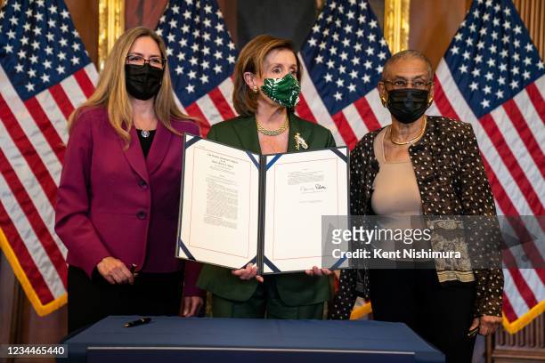 Speaker of the House Nancy Pelosi flanked by with Rep. Jennifer Wexton , left, and Del. Eleanor Holmes Norton , right, holds up a signed H.R. 3325,...