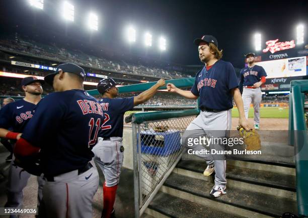 Hirokazu Sawamura of the Boston Red Sox receives a fist-bump from first base coach Tom Goodwin after pitching against the Detroit Tigers during the...