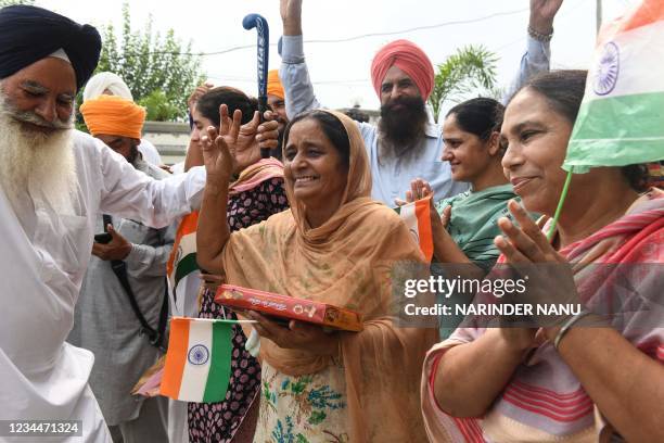 Father Baldev Singh , mother Sukhjinder Singh and relatives of India's field hockey player Gurjant Singh celebrate as India's men's hockey team beats...