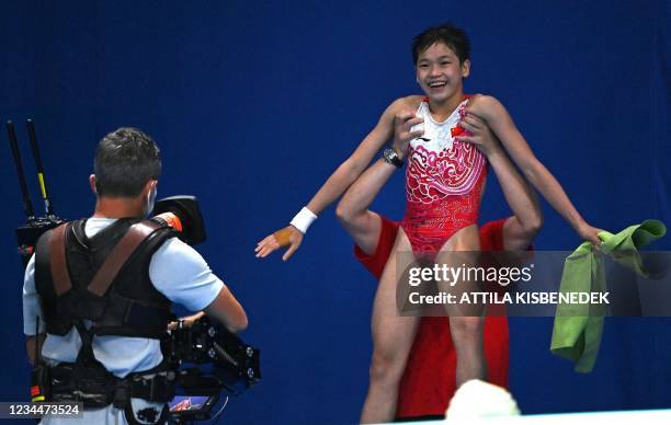 China's Quan Hongchan is lifted aloft by a coach after seeing the score and winning the women's 10m platform diving final event during the Tokyo 2020...