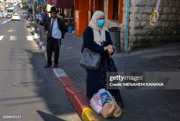 Muslim woman wearing a medical mask waits at a market in the centre of Jerusalem on August 5, 2021. - Prime Minister Naftali Bennett said on August 5...
