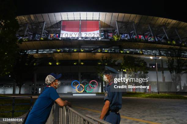 Security guard and staff member talk in front of the National Stadium during the Tokyo 2020 Olympic Games in Tokyo, Japan, on Thursday, Aug. 5, 2021....