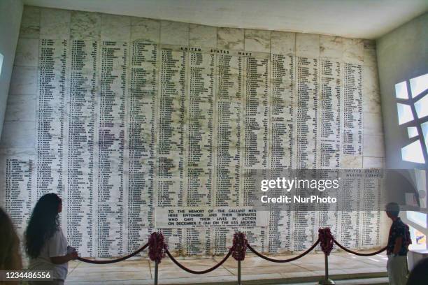 Visitors at the U.S.S. Arizona Memorial at Pearl Harbor in Hawaii, USA. Visitors reading the names of the men entombed in the wreckage below.