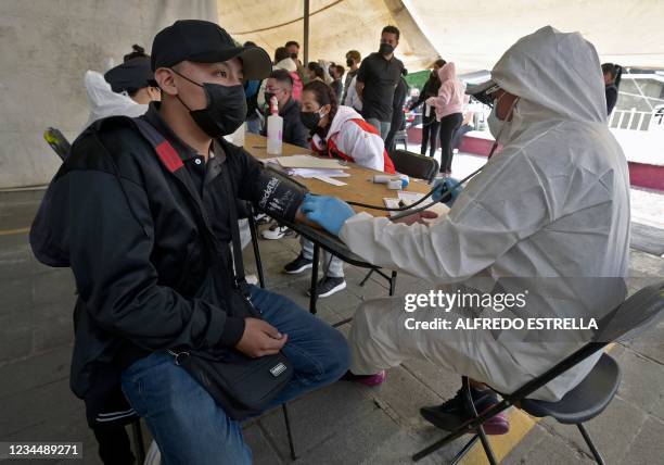Doctor from the local government checks a man's blood pressure after he had a rapid test to detect Covid-19 done in the municipal esplanade of...