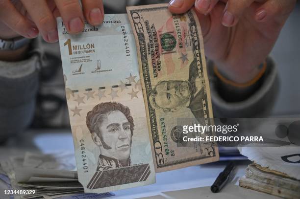Man displays Bolivar and US dollar notes at the municipal market of Catia, a neighbourhood of Caracas, on August 5, 2021. - Venezuela will eliminate...