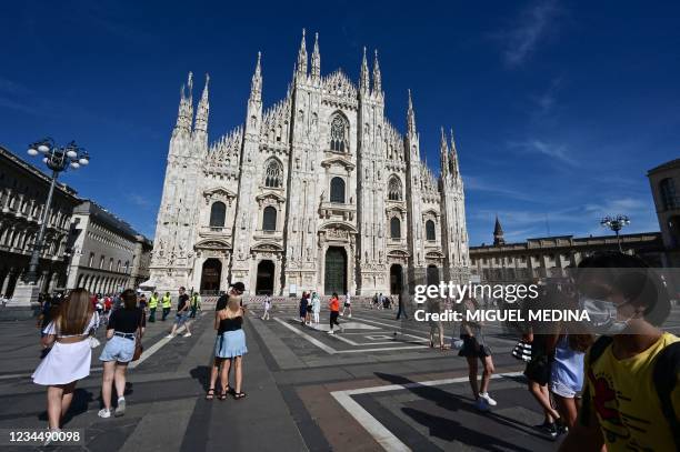 Tourists stroll on Duomo square in front of the Duomo Cathedral, centre Milan, on August 5, 2021.