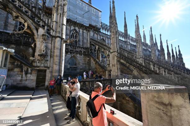 Tourists walk on the roof of the Duomo Cathedral on a sunny day in central Milan, on August 5, 2021.