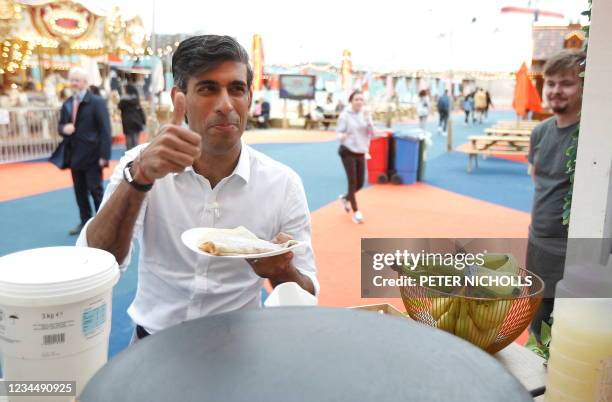 Britain's Chancellor of the Exchequer Rishi Sunak gestures as he takes a pancake from a stall at the London Wonderground comedy and music festival...