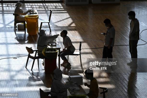 This photo taken on August 5, 2021 shows a staff member being given a nucleic acid test for the Covid-19 coronavirus at the gym of a company in Wuhan...