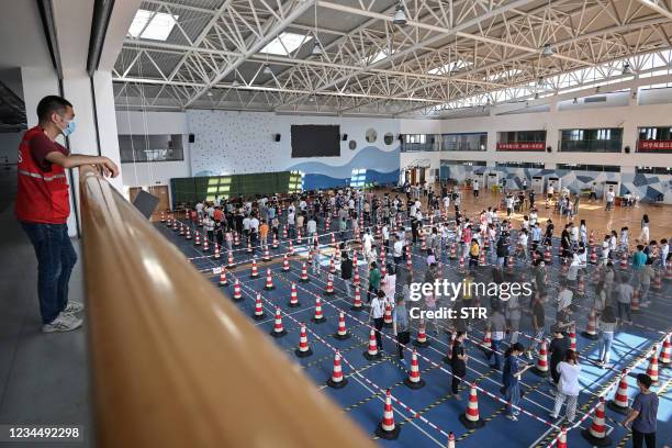 This photo taken on August 5, 2021 shows staff queueing to test for the Covid-19 coronavirus at the gym of a company in Wuhan in China's central...