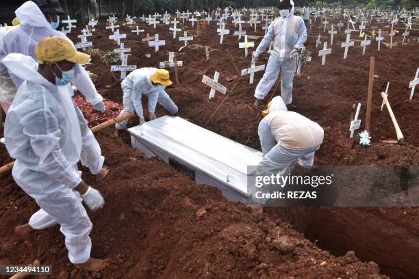 Grave diggers bury the coffin of a man who died from from the Covid-19 coronavirus at a cemetary in Bekasi on August 6 as Indonesia passed the grim...