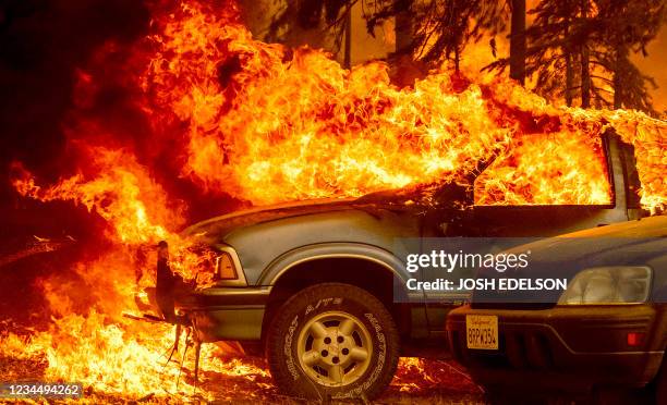 Vehicles and a home are engulfed in flames as the Dixie fire rages on in Greenville, California on August 5, 2021. - Evacuation orders were widened...