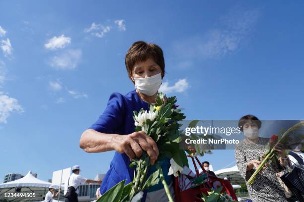 Woman wearing a face mask offers a flowers in Peace Memorial Park, as Hiroshima marks the 76th anniversary of the atomic bombing, on August 6, 2021...