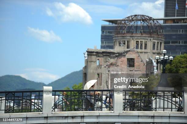 People walk in front of the Atomic Bomb Dome at the Peace Memorial Park as they attended the ceremony at the Peace Center Memory in Hiroshima for the...