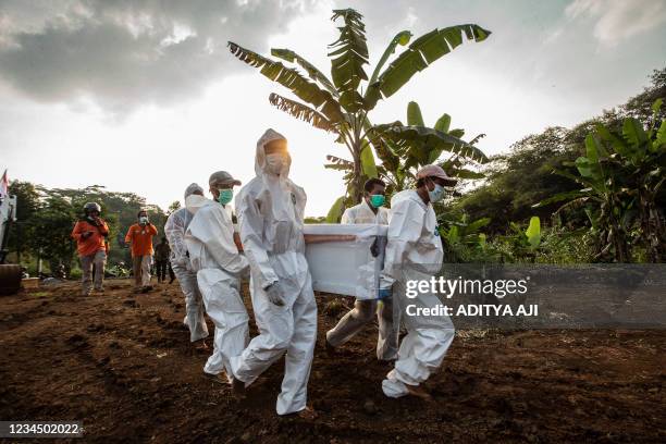 Grave diggers carry a coffin of a Covid-19 coronavirus victim for burial at a cemetary in Bogor on August 6, 2021.