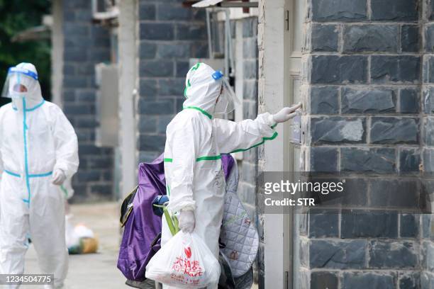 Volunteers and staff members wearing personal protective equipment against the spread of Covid-19 coronavirus carry foods and daily necessities as...