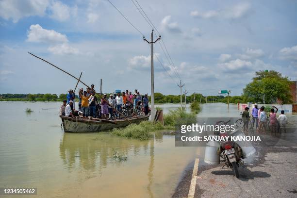 People use a boat to cross a waterlogged area after rising water level in river Ganges caused flooding at Badara Sanuti village, near Allahabad on...