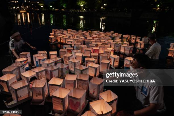 Members of local NPO release paper lanterns on Motoyasu River in front of beside the Hiroshima Prefectural Industrial Promotion Hall, as it was known...