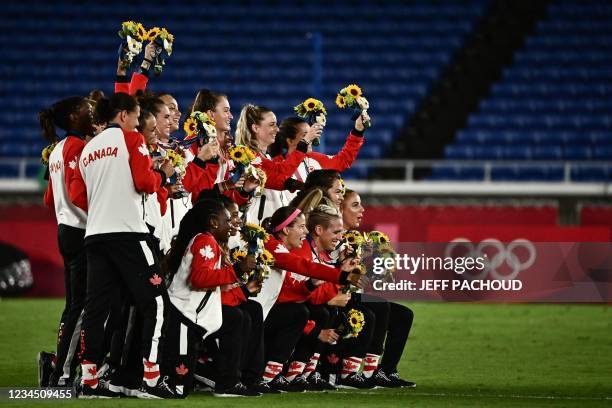 Gold medallists Canada's team pose for photos after the victory ceremony following the Tokyo 2020 Olympic Games women's final football match at the...