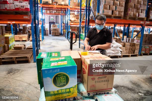 Staff member checks edible oil stock at the distribution center of a supermarket in Zhangjiajie, central China's Hunan Province, Aug. 5, 2021....