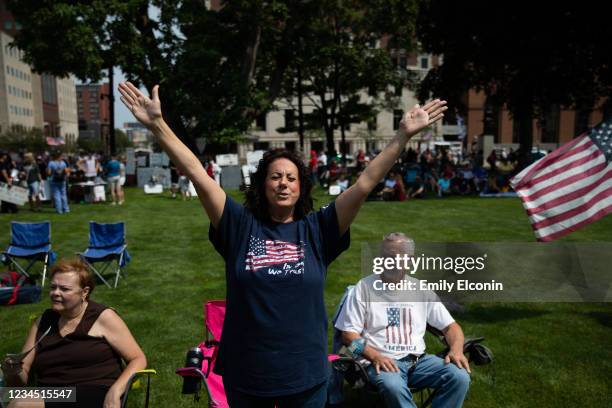 Sharon Lofquist of Twin Lakes raises her arms as she sings along to religious music as demonstrators gather to protest against mandated vaccines...