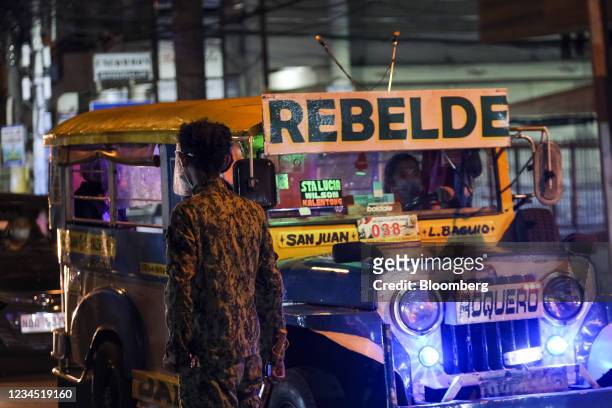 Jeepney drives past a member of the Philippine National Police in San Juan City, Metro Manila, the Philippines, on Friday, Aug. 6, 2021. The...