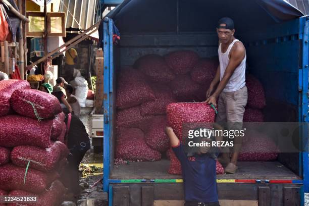 Workers unload sacks of shallots from a truck at a traditional market in Bekasi, West Java, on August 7, 2021.