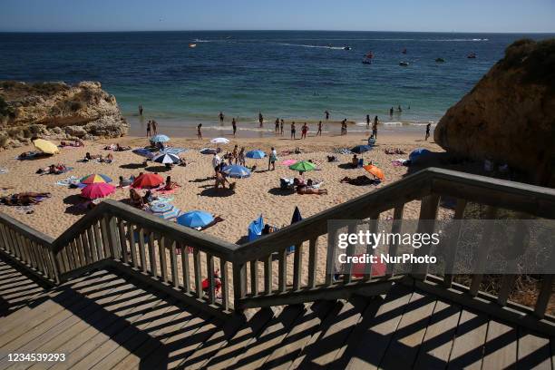 Beachgoers sunbathe and swim at Oura beach amid COVI-19 pandemic in Albufeira, Algarve region, Portugal on August 6, 2021.