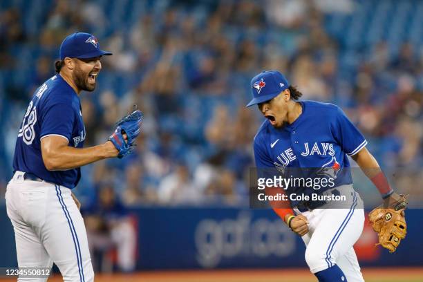 Santiago Espinal of the Toronto Blue Jays reacts next to Robbie Ray after Espinal throws Enrique Hernandez of the Boston Red Sox out at first base in...