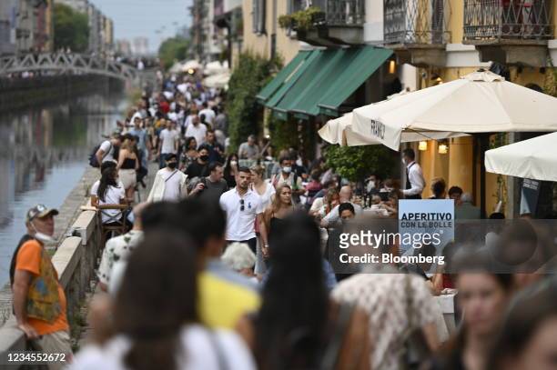 Visitors walk past restaurants in the Navigli neighborhood of Milan, Italy, on Saturday, Aug. 7, 2021. Italy will restrict many leisure activities...