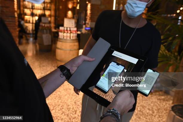 Server scans a digital "green pass" at a restaurant in the Navigli neighborhood of Milan, Italy, on Saturday, Aug. 7, 2021. Italy will restrict many...