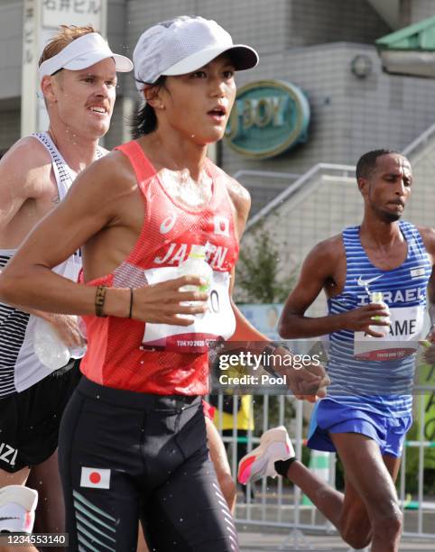 Japan's Suguru Osako holds water at the refreshment point while competing in the men's marathon finalon day sixteen of the Tokyo 2020 Olympic Games...