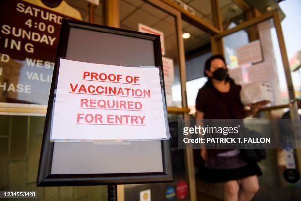Sign stating proof of a Covid-19 vaccination is required is displayed outside of Langer's Deli in Los Angeles, California on August 7, 2021. - The...
