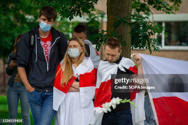 Protesters draped with flags stand in silence during the demonstration. 1 year anniversary march for Belarus. A protest march from the Malieveld to...