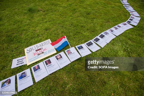 Paper-chain of photos showing some of the 600 victims incarcerated by President Alexander Lukashenkos regime are placed on the grass during the...