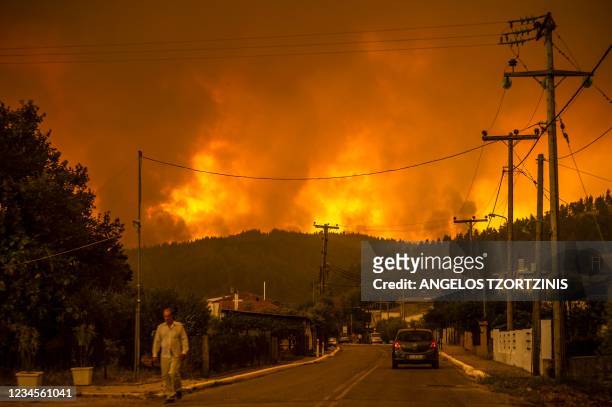 Local resident walks as a wildfire rages near the village of Gouves, on Euboea island, second largest Greek island, on August 8, 2021. - Hundreds of...