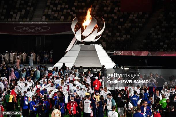 Athletes gather by the The Olympic Cauldron and the Olympic flame to celebrate during the closing ceremony of the Tokyo 2020 Olympic Games, at the...