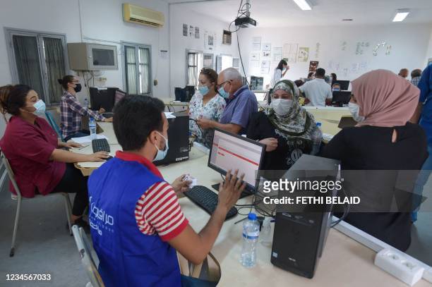 Health workers register people for vaccination at an inoculation center at the Ariana pilot high school in the eponymous governorate near the capital...