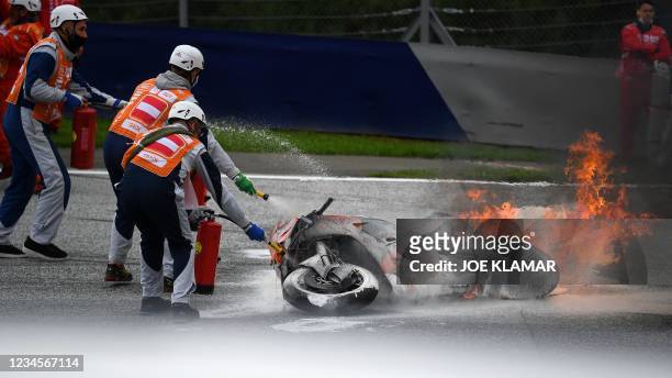 Track marshals try to extinguish the fire on a motorbike following a crash involving Aprilia Italian rider Lorenzo Savadori and KTM Spanish rider...