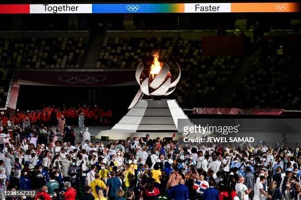 Atheletes celebrate by the Olympic Cauldron and the Olympic flame during the closing ceremony of the Tokyo 2020 Olympic Games, at the Olympic...