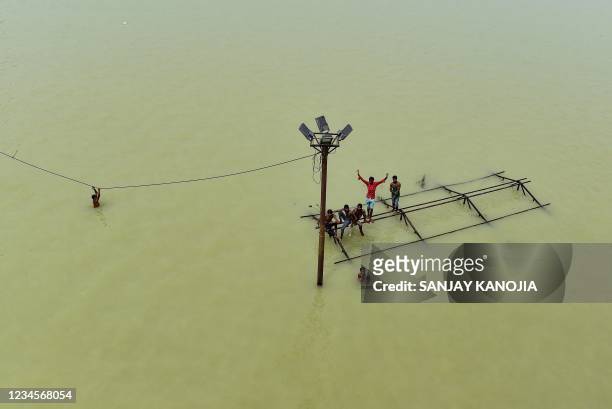 Boys along with local boatmen play atop a submerged structure at Daraganj Ghat, one of the flooded banks of the Ganges River in Allahabad on August...