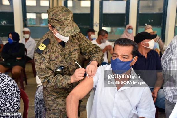 An army officer administers the AstraZeneca vaccine to a Tunisian man at Oued Ellil high school in Manouba. The national Covid-19 vaccination day for...