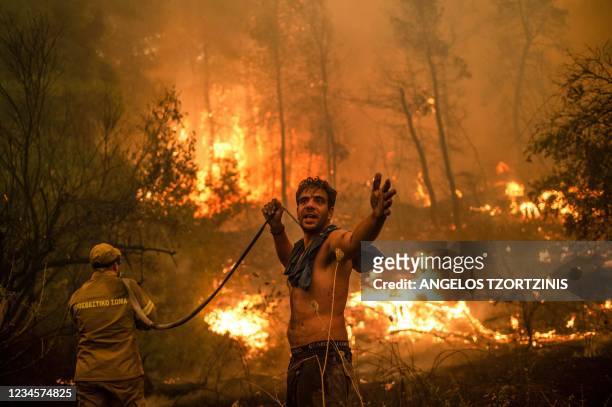 Local resident gestures as he holds n empty water hose during an attempt to extinguish forest fires approaching the village of Pefki on Evia island,...