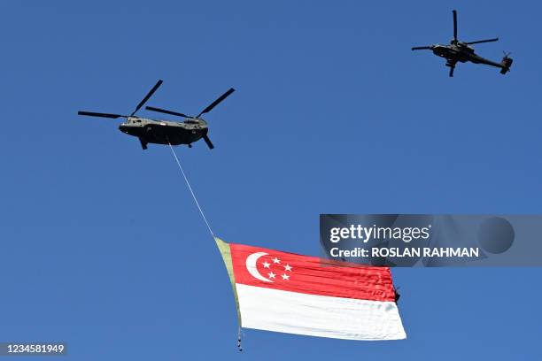 Republic of Singapore Air Force Chinook helicopter is escorted by an Apache helicopter over the city as they parade the Singapore flag to mark the...