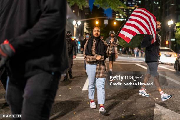 An anti-fascist protester flies an upside down American flag on August 8, 2021 in Portland, Oregon. Anti-fascists and far-right extremists clashed...
