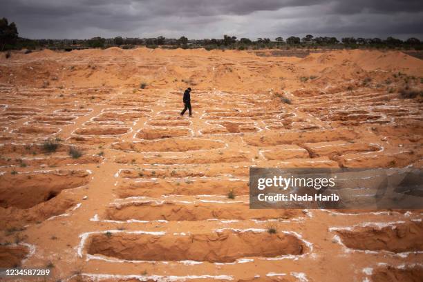 Member of the General Authority for Search and Identification of Missing Persons team walks through the mass grave site on March 24, 2021 in Tarhuna,...