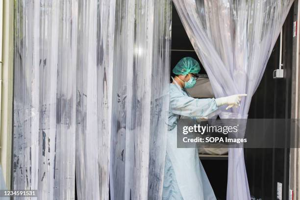 Medical worker wearing a Personal Protective Equipment seen closing the curtain of a mortuary made from intermodal container in Thammasat's hospital...