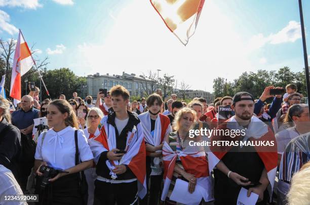 Demonstrators hold placards and wear Belarusian flags during a rally called "We won't forget, We won't forgive!" in Vilnius on August 9 one year...