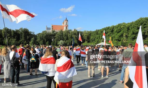 Demonstrators hold placards and wear Belarusian flags during a rally called "We won't forget, We won't forgive!" in Vilnius on August 9 one year...